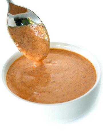 Spoon dipping into a small bowl of creamy chipotle sauce