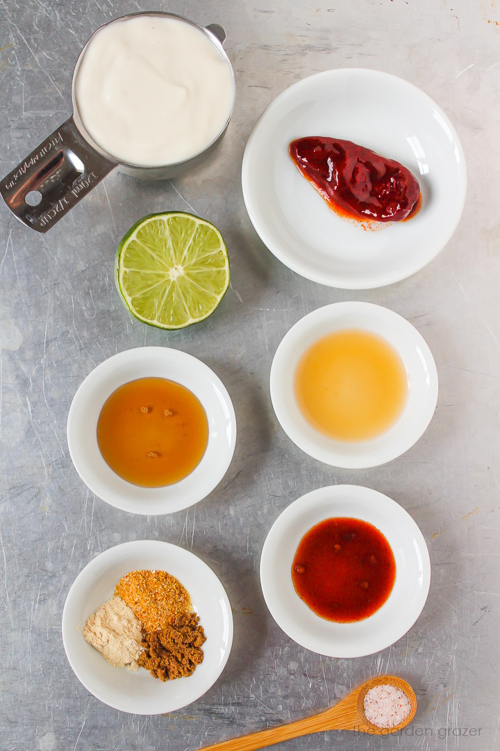 Dairy-free yogurt, lime, vinegar, maple syrup, and spice ingredients laid out on a metal tray