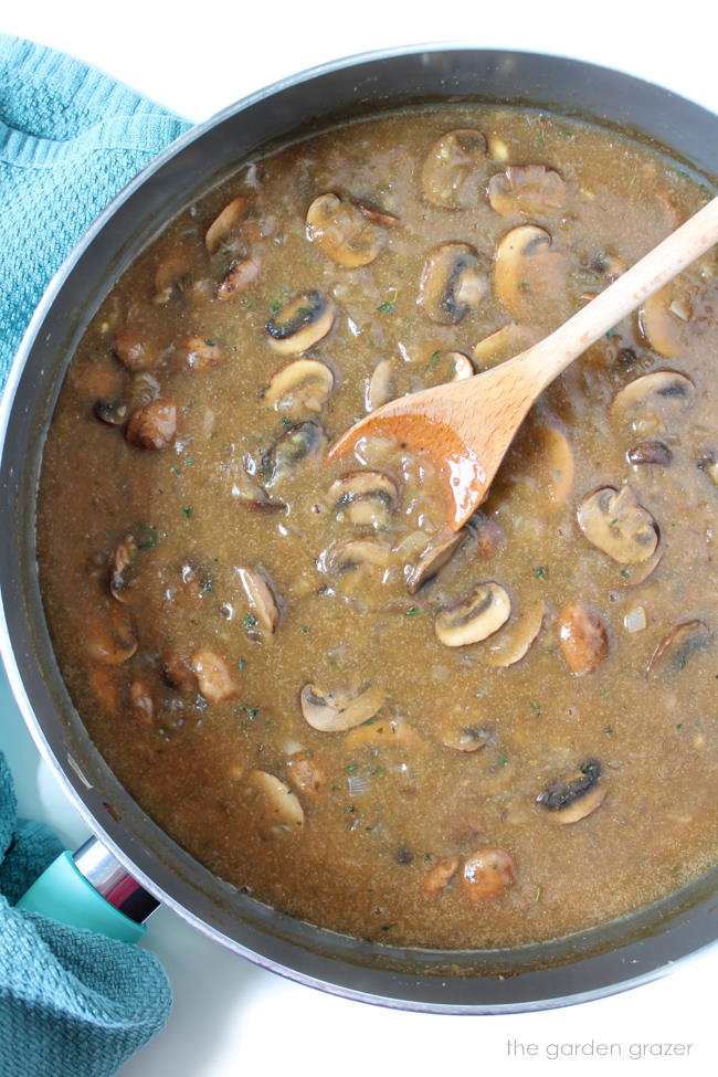 Preparing sauce in a large skillet with wooden spoon