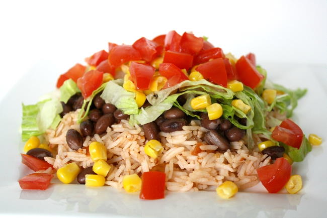 Brown rice, black beans, and fresh vegetables on a plate