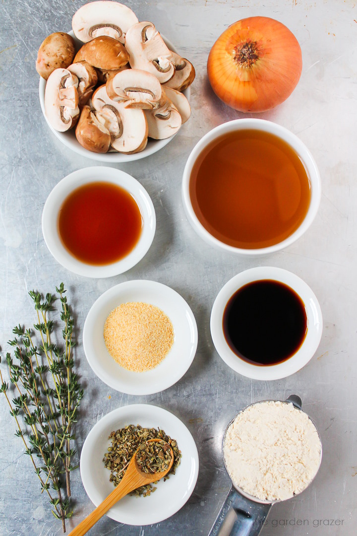 Onion, vegetable broth, red wine vinegar, tamari, flour, fresh thyme, and seasoning ingredients laid out on a metal tray