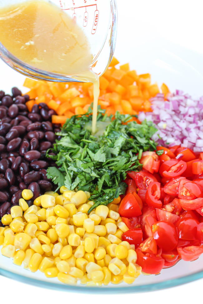 Southwest black bean salad preparation with dressing pouring over top