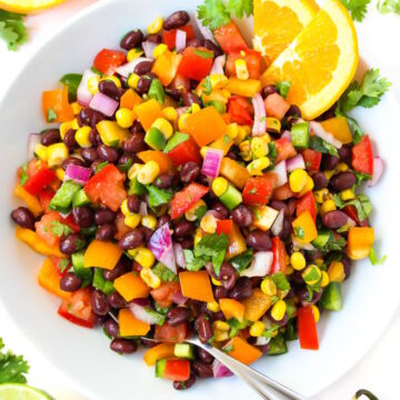 Overhead view of southwest black bean salad with citrus dressing in a white serving bowl with spoon