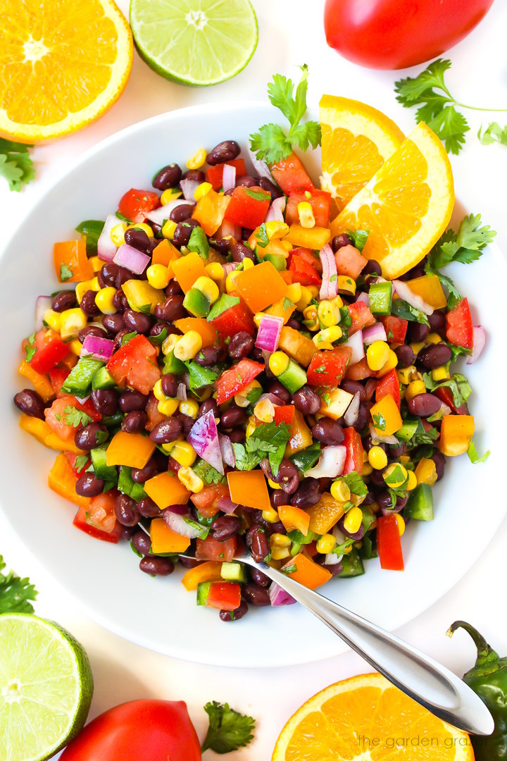 Overhead view of southwest black bean salad with citrus dressing in a white serving bowl with spoon