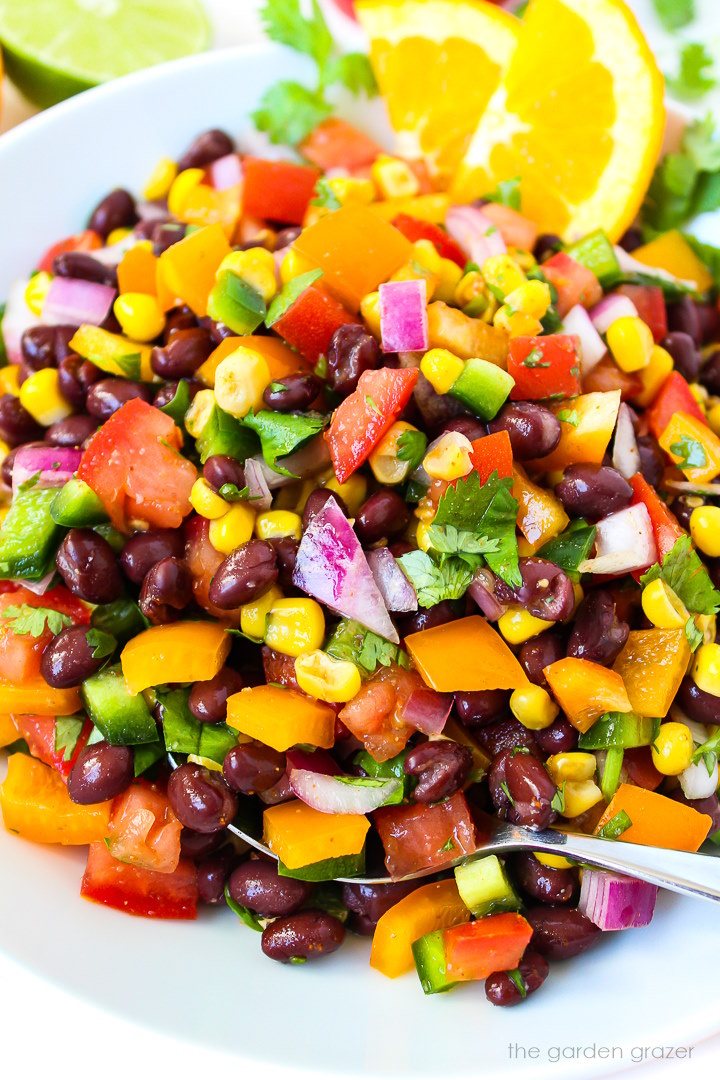 Close up view of southwest black bean salad on a white plate with serving spoon