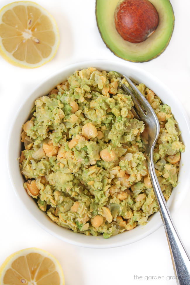 Preparing the chickpea avocado mash in a white bowl with fork