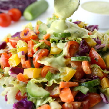 Rainbow chopped salad being topped with avocado dressing