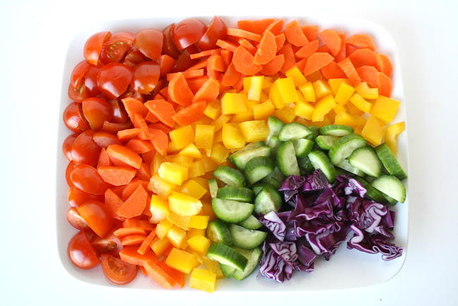 Ingredients for rainbow chopped salad arranged on a white plate