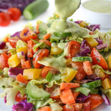 Vegan rainbow chopped salad on a white plate with avocado dressing