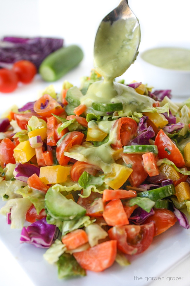 Vegan rainbow chopped salad on a white plate with avocado dressing