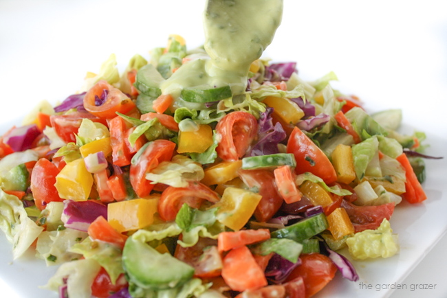 Dressing being poured on a rainbow chopped salad