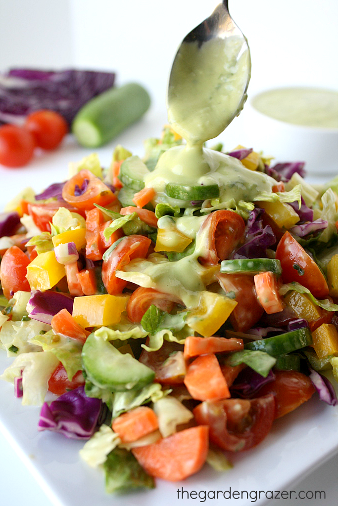 Rainbow chopped salad being dressed with creamy lemon basil dressing