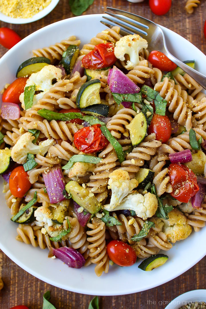Roasted vegetable pasta with basil and balsamic dressing in a white serving bowl