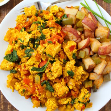 Overhead view of spinach tofu scramble on a white serving plate with fork