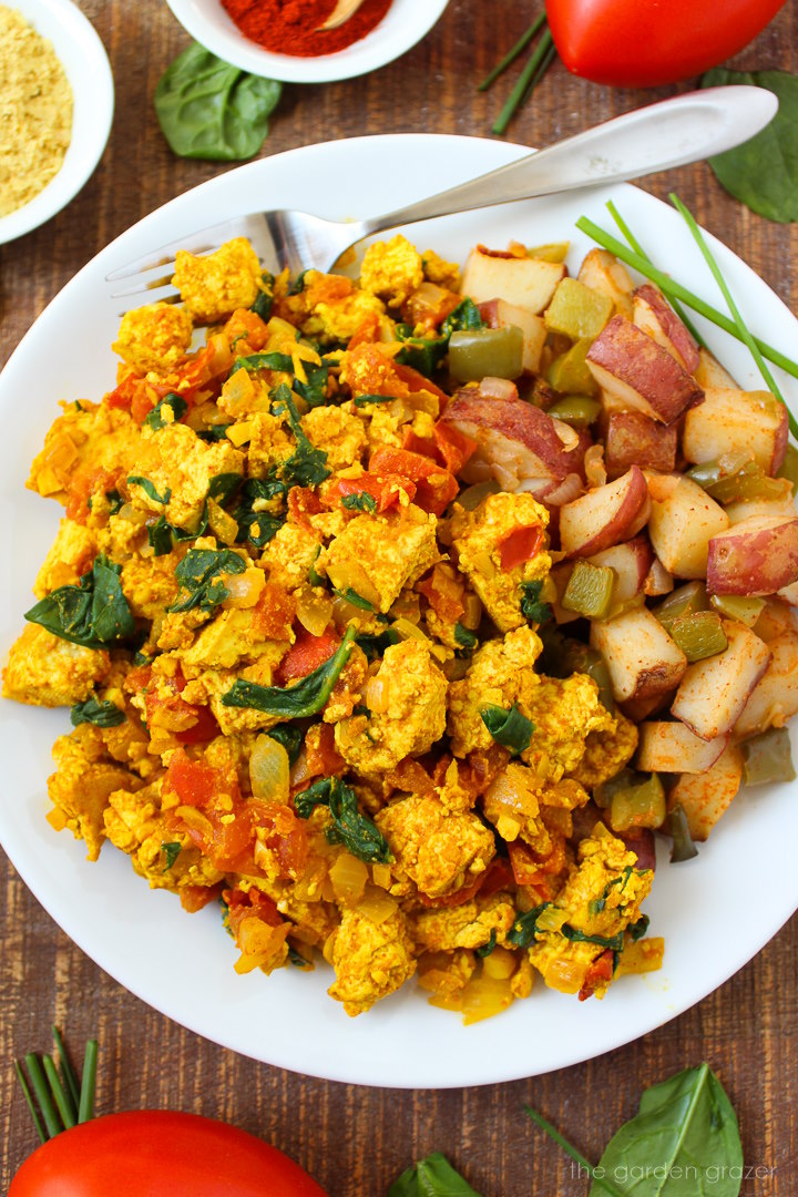 Overhead view of spinach tofu scramble on a white serving plate with fork