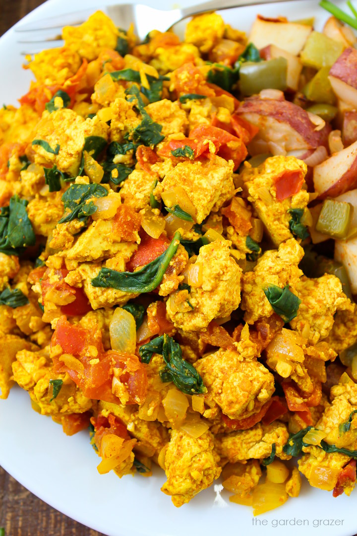 Close up view of tomato and spinach tofu scramble served on a white plate