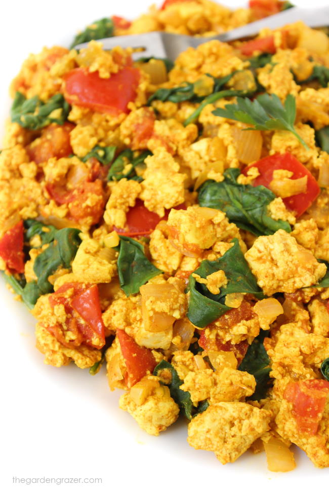 Tofu scramble with spinach and tomato on a plate with fork