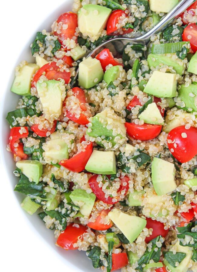 Vegan quinoa avocado salad with spinach and tomatoes in a bowl