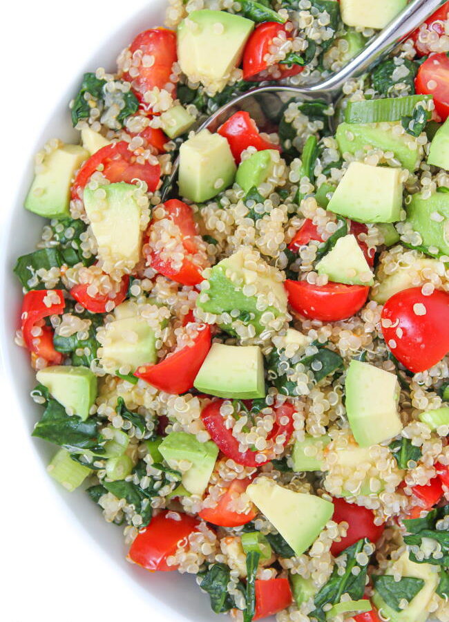 Vegan quinoa avocado salad with spinach and tomatoes in a bowl