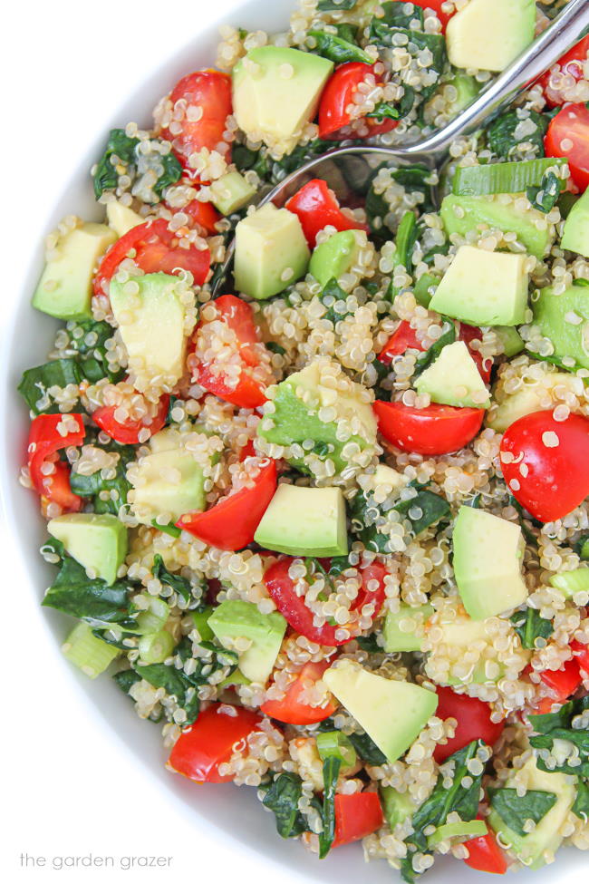 Vegan quinoa avocado salad with spinach and tomatoes in a bowl