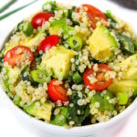 Quinoa avocado spinach power salad with tomato in a small white bowl