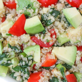 Bowl of vegan quinoa avocado salad with tomato and spinach