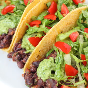 Vegan black bean tacos with lettuce, tomato, and avocado cream sauce