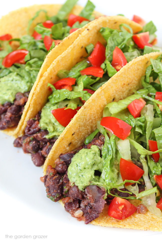 Vegan black bean tacos with lettuce, tomato, and avocado cream sauce