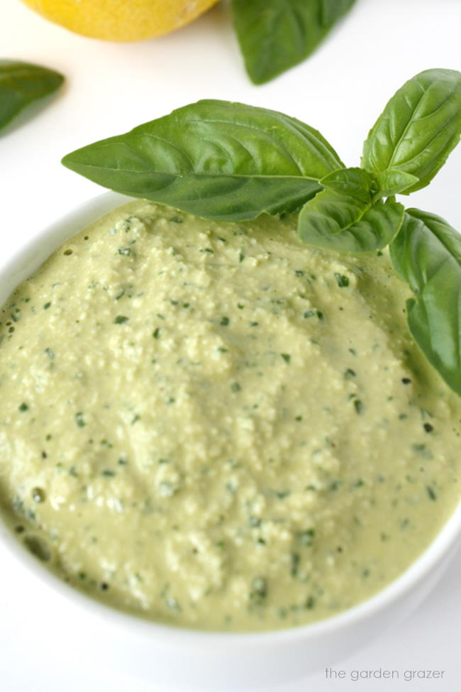 Dairy-free cashew pesto in a small bowl with fresh basil on the side