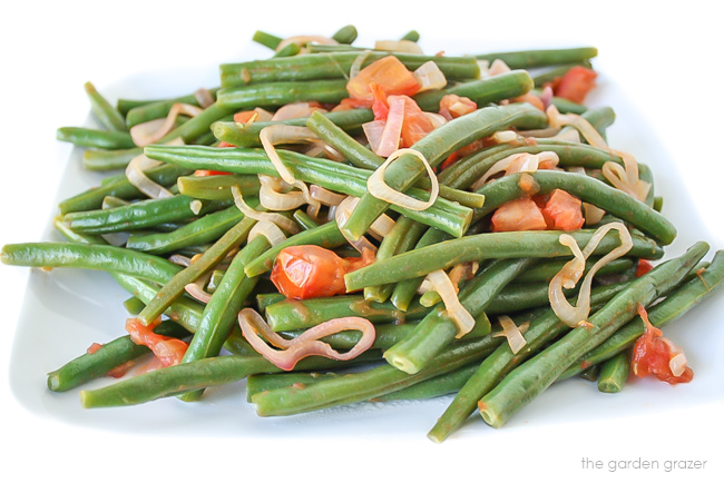 Plate of cooked green beans in shallots and tomatoes