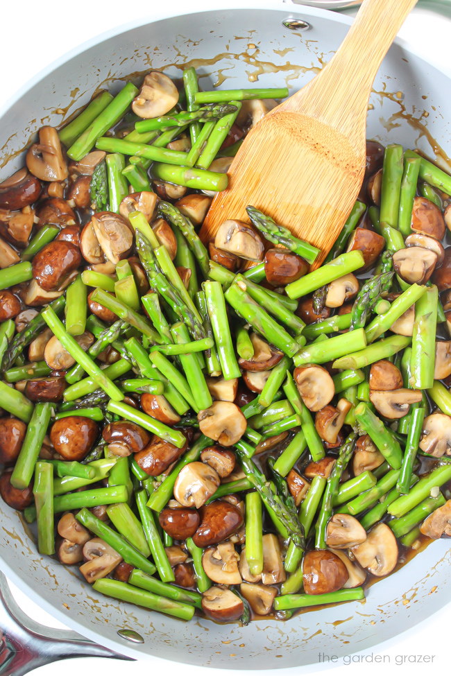 Fresh vegetable stir-fry cooking in a skillet with wooden spatula