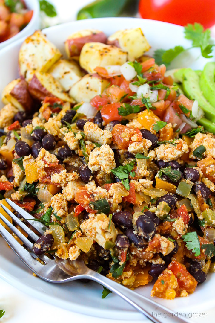 Close up view of black bean southwest tofu scramble on a white plate with serving fork