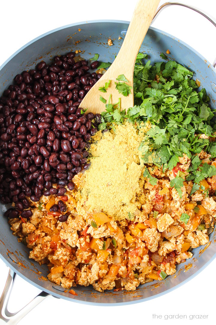 Overhead view of preparing breakfast scramble ingredients in a large skillet before stirring together