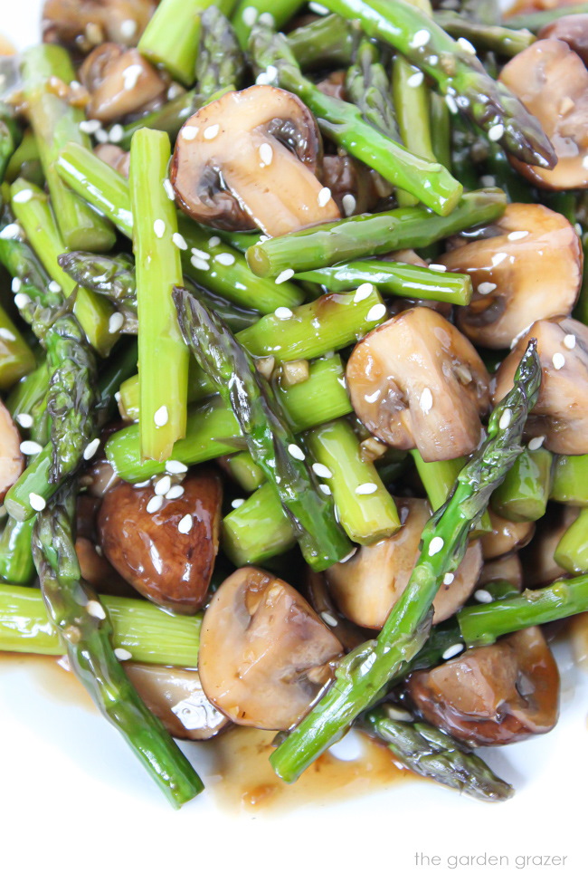 Close-up view of asparagus stir-fry with sesame seeds on a white plate