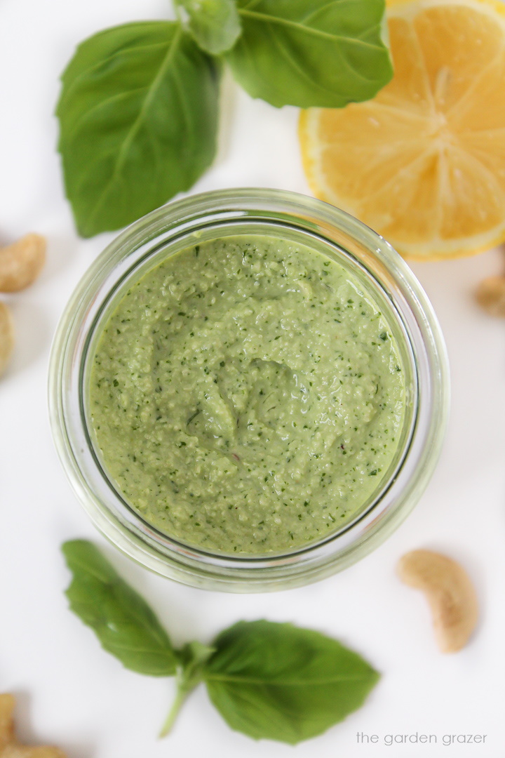 Dairy-free cashew pesto in a small jar with fresh basil on the side