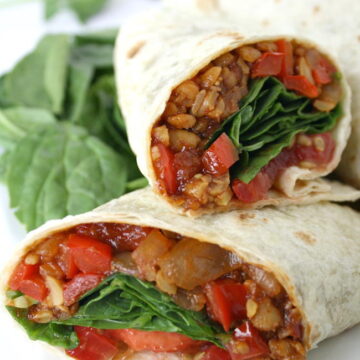 Vegan BBQ tempeh wrap halves on a plate with spinach