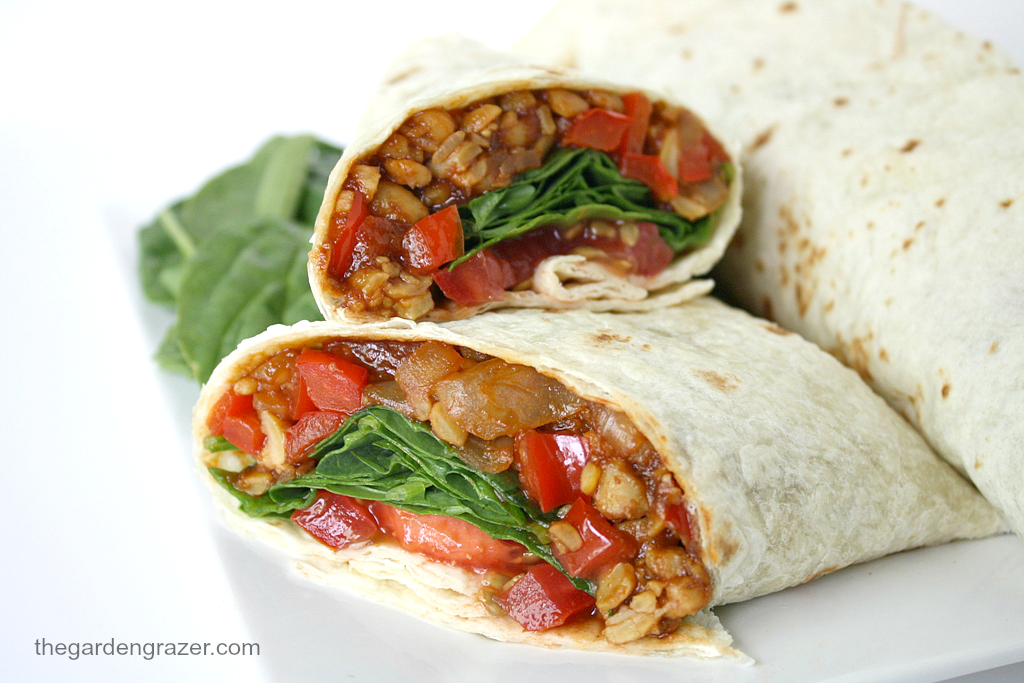 Plate with vegan BBQ tempeh wraps with tomato and spinach