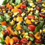 Vegan wild rice salad with spinach and vegetables on a white plate