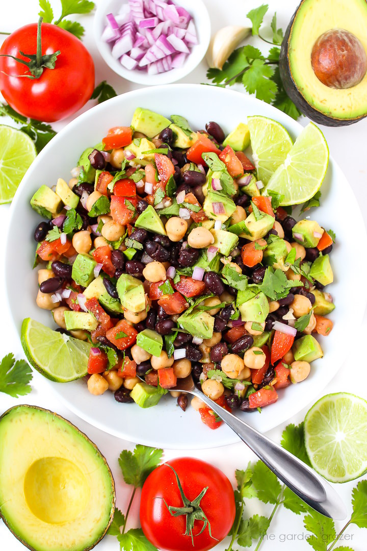 Overhead view of vegan fiesta bean salad with cumin-lime dressing in a white bowl with lime slices