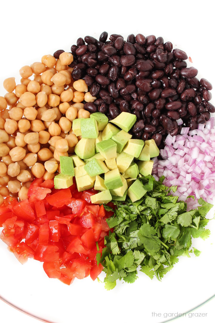 Preparing ingredients for salad in a large glass bowl before stirring together