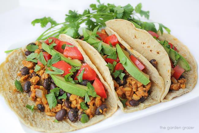 Vegan tempeh and black bean tacos on a white plate