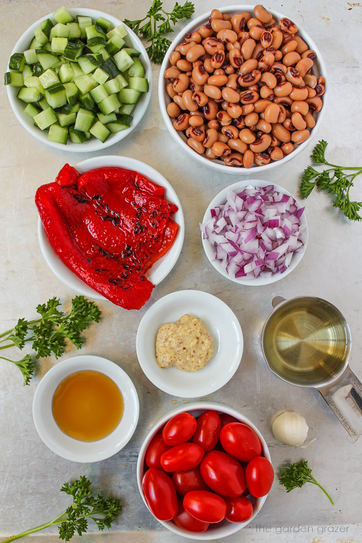 Red pepper, cucumber, onion, tomatoes, vinegar, mustard, and fresh herb ingredients laid out on a metal tray