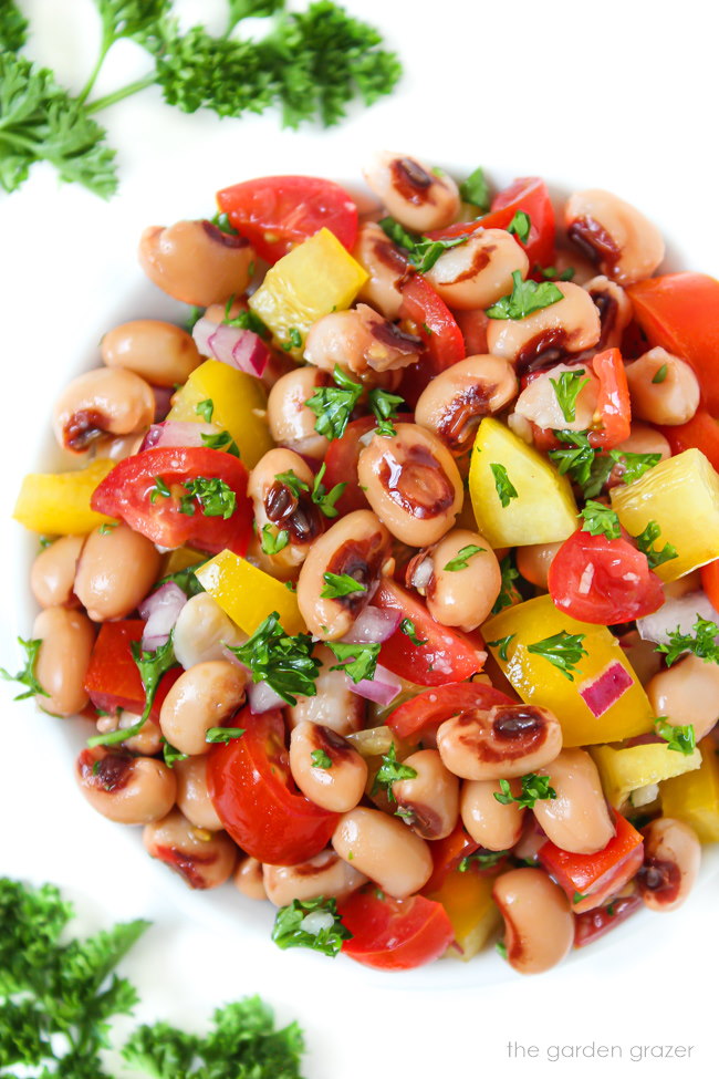 Close up view of bean salad in a white bowl with fresh herbs