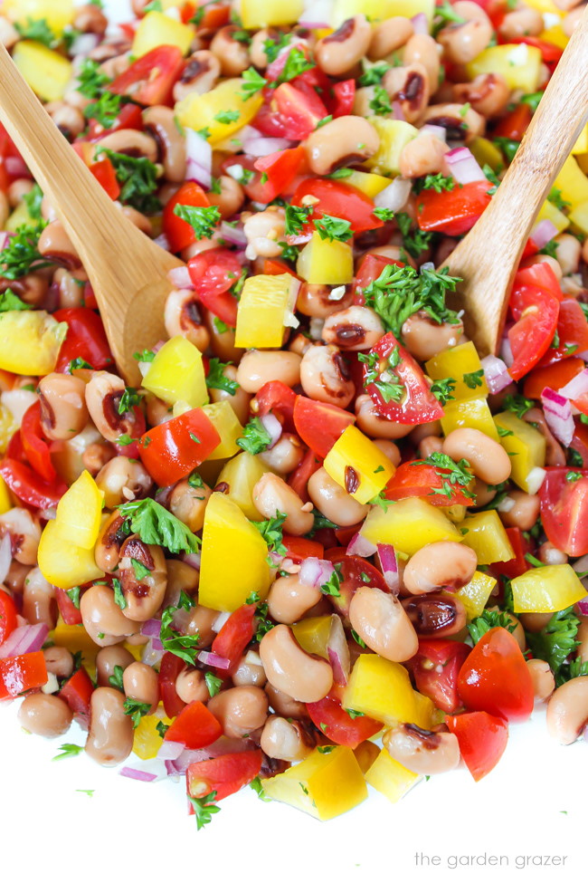 Tossing together a vegan black eyed pea salad with tomatoes and bell pepper