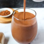Vegan healthy chocolate milkshake being poured into a serving glass