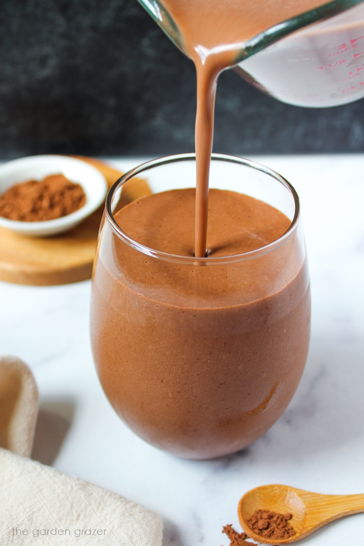 Vegan healthy chocolate milkshake being poured into a serving glass