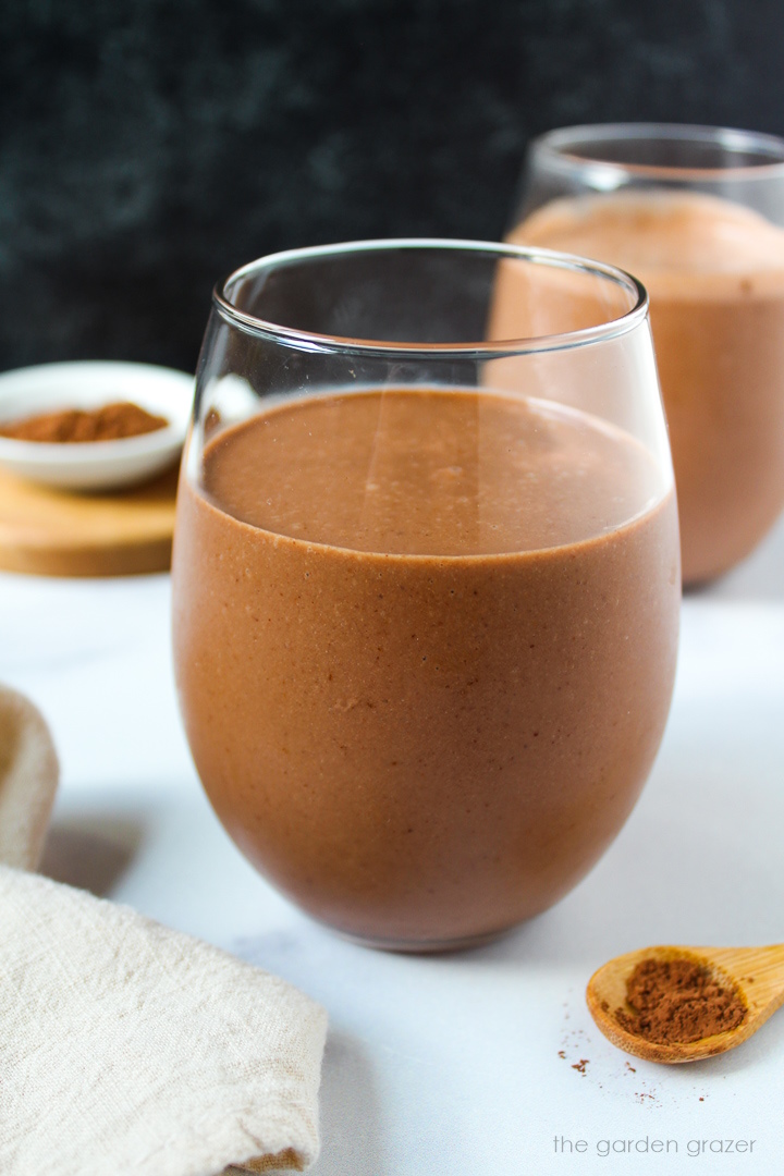 Healthy chocolate milkshake in a serving glass on a white table