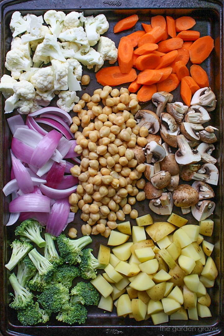 Chopped vegetables and chickpeas on a sheet pan before baking