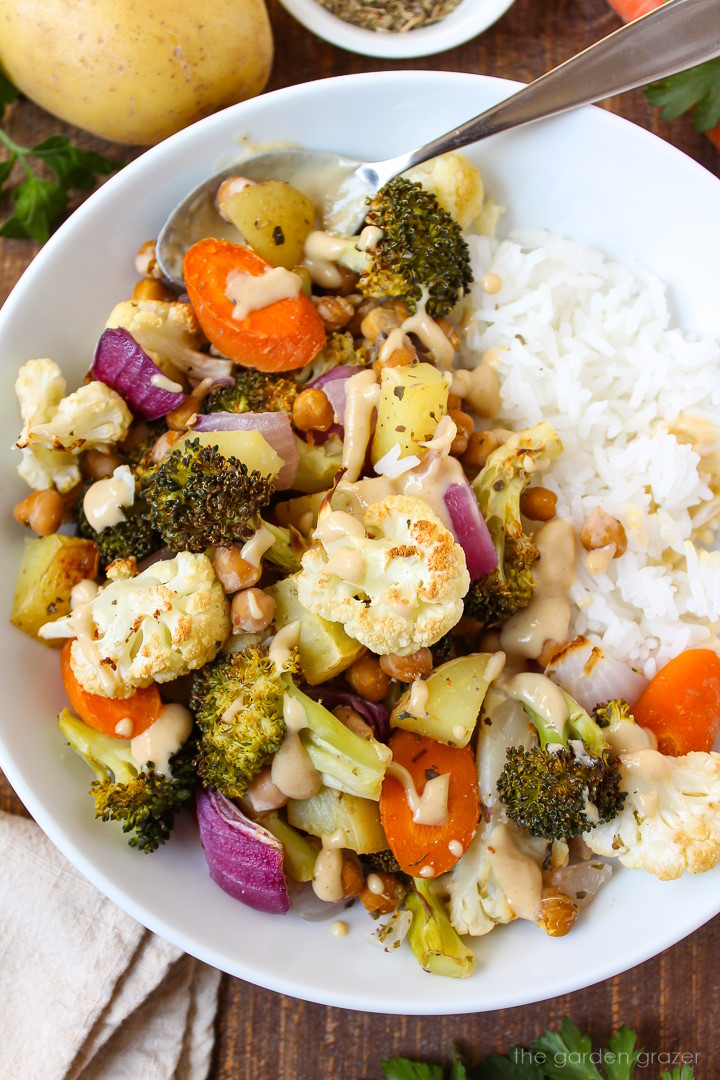 Overhead view of roasted vegetables and chickpeas with rice and tahini sauce