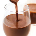 Healthy vegan chocolate milkshake being poured into glasses